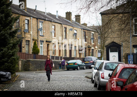 Una matura signora camminando sulle strade di ciottoli in Lodge Street Littleborough, Rochdale, Lancashire, Inghilterra, Regno Unito. Foto Stock