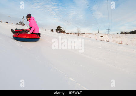 Madre e figlio divertirsi sulla neve a tubo, a bellezza giornata invernale Foto Stock