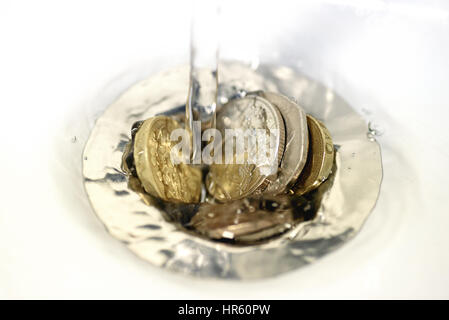 British denaro inclusa una libbra di moneta bloccato in un dissipatore di scarico di scarico come flussi di acqua sopra le monete. Foto Stock