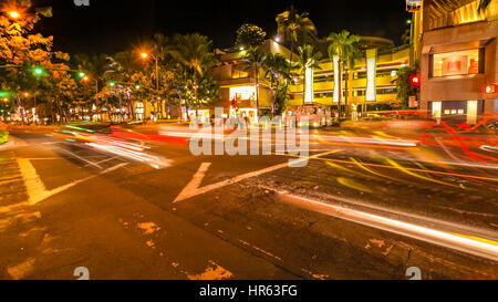 HONOLULU OAHU, HAWAII, Stati Uniti d'America - 21 agosto 2016: automobili attraversando la Kalakaua Ave e Mare Ave bivio in motion blur con strade luci. Urban vicina Foto Stock