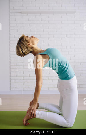 Un attraente giovane donna facendo un po' di yoga posa per equilibrio e allungamento. foto verticale concetto sano Foto Stock