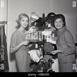 Degli anni Cinquanta, storico, due elegantemente vestito ladies stand da un cappello display. Foto Stock