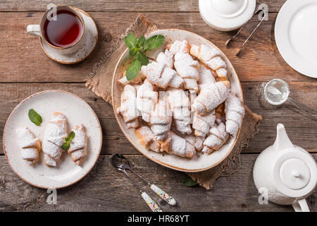 Rugelach con marmellata al riempimento sulla piastra con tè su sfondo di legno, vista dall'alto con spazio di copia Foto Stock