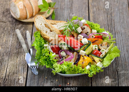 Grigliata mista di stile greco con verdure e formaggio feta su insalata verde servita con pane tostato Foto Stock
