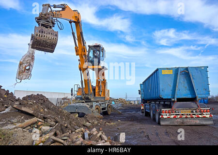 Un Liebherr LH24 gru mobile con idraulico della cabina rialzata e dotata di un ordinamento di benna a gancio è lo smistamento dei rifiuti da detriti. Focus sul conducente in cabina. Foto Stock