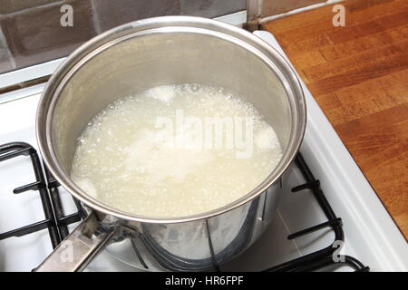 Casseruola di riso in acqua bollente su un piano cottura a gas Foto Stock