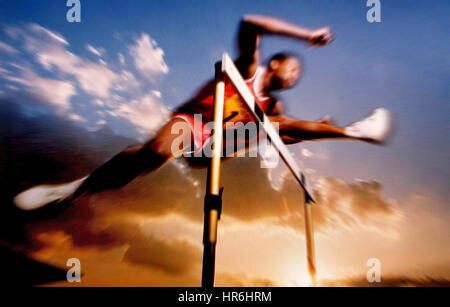 HURDLER drammatico vista a basso angolo di Hurdler volare sopra un hurdle al tramonto indossando 'numero 1' sport T shirt effetto blur velocità Ian Shaw Kodak Photographer Foto Stock