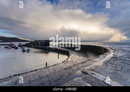 Lyme Regis, Dorset, Regno Unito. Il 27 febbraio, 2017. Regno Unito Meteo. Un enorme tempesta cloud recede nella distanza poco prima del tramonto, dopo che essa aveva earler passata sopra il porto di Cobb a Lyme Regis nel Dorset. Photo credit: Graham Hunt/Alamy Live News Foto Stock