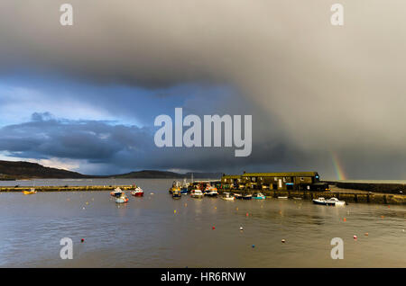 Lyme Regis, Dorset, Regno Unito. Il 27 febbraio, 2017. Regno Unito Meteo. Un enorme tempesta cloud con un piccolo arcobaleno, retrocede nella distanza dopo che essa aveva earler passata sopra il porto di Cobb a Lyme Regis nel Dorset. Photo credit: Graham Hunt/Alamy Live News Foto Stock