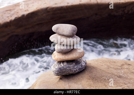 Una pila di rocce bilanciate con acqua sullo sfondo Foto Stock