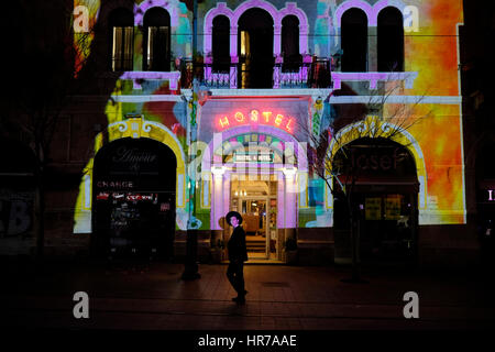 Ultra un ebreo ortodosso a piedi davanti a un edificio che è illuminato con luce mostra la proiezione in Jaffa street durante l annuale Shaon Horef 2017 (Winter Festival di rumore) aprire la cultura festival che si svolge in febbraio per le strade di Gerusalemme ovest Israele Foto Stock