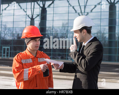 Boss o capo dando una tangente o illegale stipendio inoficcial in una busta in contanti. Boss che mostra il silenzio segno. Business background moderno. Foto Stock