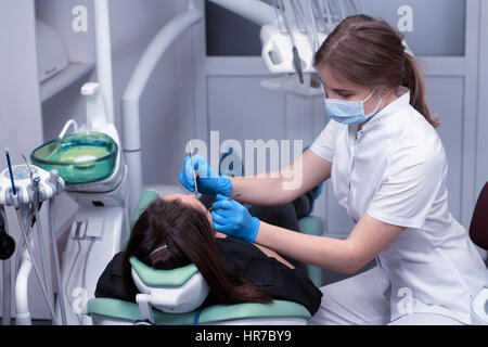 Dentista a lavori esaminando donna di denti nella clinica dentale Foto Stock