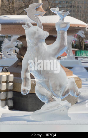 Sculture di ghiaccio a Ottawa, in una giornata di sole con il parco della città e gli edifici dietro. Scupltrure di ghiaccio è di un orso con un uccello sulla testa Foto Stock