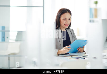 Ritratto di successo imprenditrice asiatici occupato a lavorare alla scrivania in ufficio moderno, lo smistamento delle cartelle con i documenti e documentazione Foto Stock