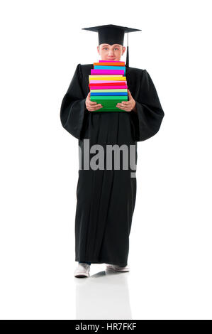 Studente maschio portano pesanti libri. A piena lunghezza Ritratto di un giovane uomo di graduazione nel mantello di contenimento della pila di libri isolati su sfondo bianco. Foto Stock