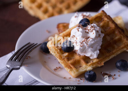 Waffle belga sulla piastra bianca, igienico e rustico sfondo. Foto Stock