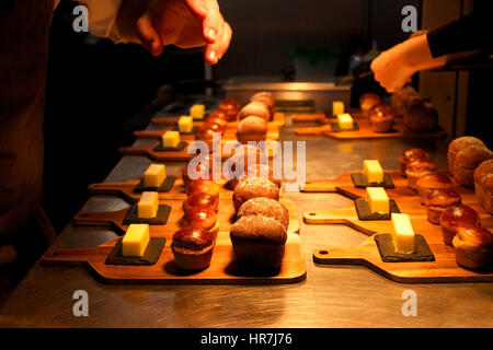 I piccoli rotoli di pane fatto in casa e le piazze di burro su assi di legno posati su silver top da cucina pronti per essere serviti in un ristorante, gli chef ha Foto Stock