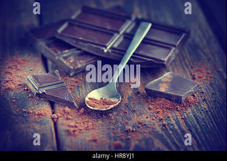 Il cioccolato scuro su backround in legno con un po' di polvere di cacao Foto Stock