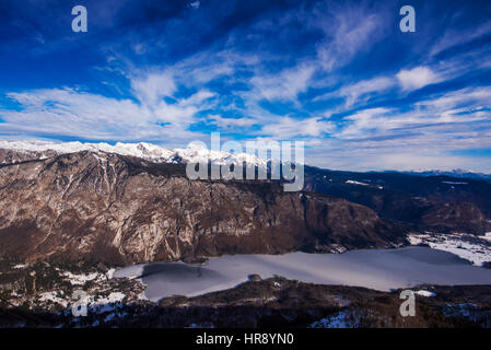 Monte Triglav picco congelate di cui sopra il lago di Bohinj in Slovenia sulla luminosa giornata invernale Foto Stock