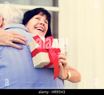 Moglie abbracciando il marito per il presente Foto Stock