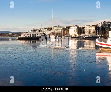 In inverno il porto di Oslo Norvegia, Aker Brygge, Tjuvholmen e Nesodden traghetto passeggeri riflessa nelle acque del fiordo e nuovo ice Foto Stock