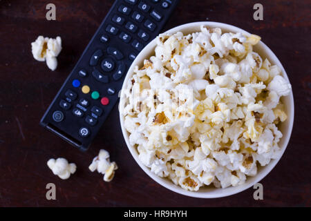 Il Popcorn in una vaschetta di colore bianco con il telecomando della TV controler Foto Stock