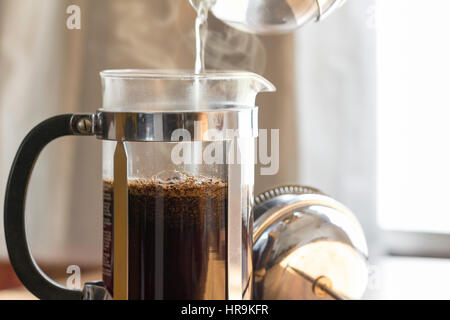 Per l'infusione di caffè in una pressa francese nella calda luce del mattino che mostra la preparazione della bevanda di caffè. Si tratta di un studio shot con copia spazio sulla destra. Foto Stock