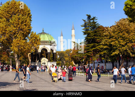 La popolazione locale e i turisti a piedi intorno all area di Sultanahmet neat Moschea Blu in Istasnbul. Fontana di tedesco e minareti della Moschea Blu sono in backgroun Foto Stock