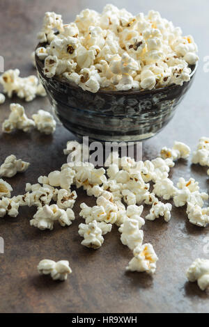 Il Popcorn nel recipiente di ceramica su sfondo arrugginito. Foto Stock