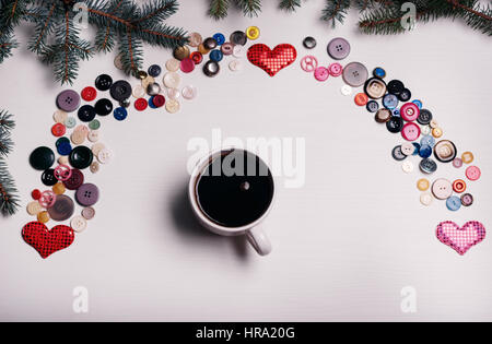 La scheda di colore bianco con un sacco di pulsanti in un set di arcobaleno e la tazza di caffè nel mezzo il giorno di San Valentino Foto Stock