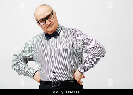 Elegante bossy pensionati Uomo in camicia a righe con il filtro bow tie in piedi con le mani sui fianchi e guardando la telecamera piercingly Foto Stock