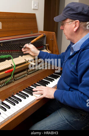 Un sintonizzatore di piano di messa a punto di un pianoforte verticale, London, Regno Unito Foto Stock