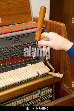 Un sintonizzatore di piano di messa a punto di un pianoforte verticale, London, Regno Unito Foto Stock