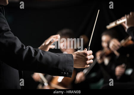 Il conduttore dirigere Symphony orchestra con esecutori su sfondo, mani di close-up. Foto Stock