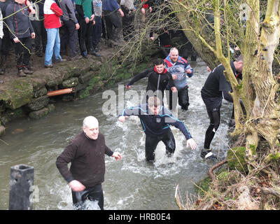 Ashbourne, Derbyshire, Regno Unito. Il rumble annuale tra il Uppards e Downards che è Ashbourne Royal Shrovetide Footabll luogo. Essenzialmente un gigante scrum di rugby che si svolge in tutta la città, i giocatori hanno per obiettivo la sfera in corrispondenza di uno dei due obiettivi e quale squadra si gioca per dipende dal fatto che vi sono nati verso l'alto o verso il basso del ruscello Henmore che greggi attraverso la città. Il tutto avviene di nuovo domani (1 marzo), il Mercoledì delle Ceneri. Scrambling dei giocatori di ottenere dal ruscello Henmore per seguire la sfera. Foto Stock