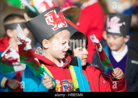 Giorno di san Davide celebrazioni come scuola bambini marzo attraverso la cittadina di Colwyn Bay, il Galles del Nord con bandiere gallese e narcisi Foto Stock