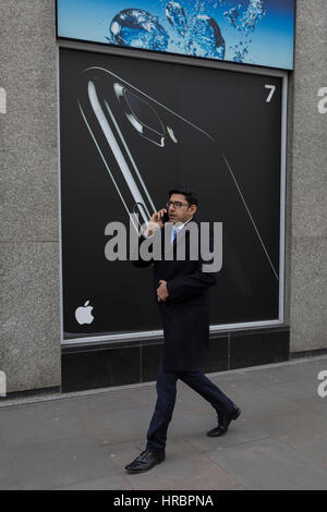 Un utente dello smartphone a piedi passato un annuncio pubblicitario per Apple iPhone7, il 16 febbraio 2017, nella città di Londra, Inghilterra. Foto Stock
