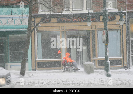 Persona disabile in carrozzella naviga Snowstorm Downtown Portland Maine tempesta di neve snow New England USA meteo ghiaccio freddo inverno Foto Stock