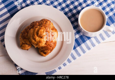 Tazza di caffè fresco e croissant cotta su un bianco sullo sfondo di legno Foto Stock