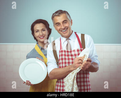 Vintage sorridente giovane nel grembiule per lavare i piatti insieme Foto Stock