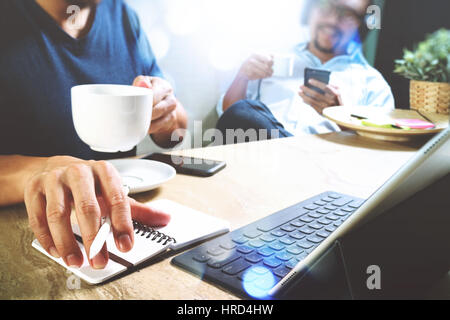 Co sito di lavoro dei progettisti che lavorano in ufficio e in possesso di una tazza di caffè,lavorando su smart phone e digital computer tablet docking sulla smart keyboar Foto Stock