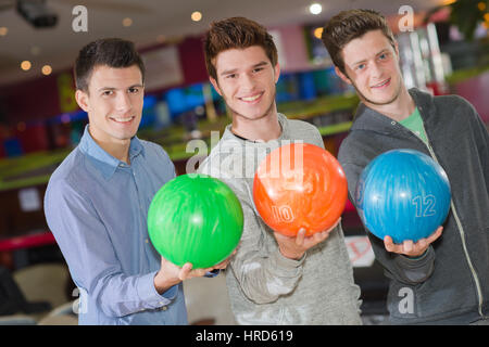 Tre uomini che tengono le palle da bowling Foto Stock