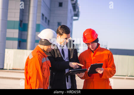 Boss o capo incarica il giovane team di giovani ingegneri con un progetto di costruzione su tablet. Tecnologia nel lavoro. Business background moderno Foto Stock