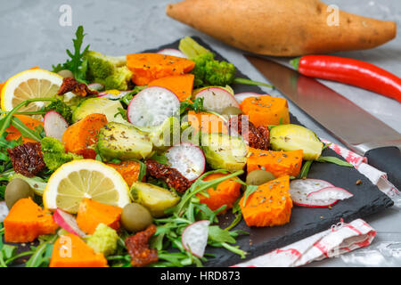 Cotto a vapore la patata dolce, broccoli e altre verdure su insalata di ardesia. Amore per un sano cibo vegan concept Foto Stock