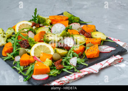 Cotto a vapore la patata dolce, broccoli e altre verdure su insalata di ardesia. Amore per un sano cibo vegan concept Foto Stock