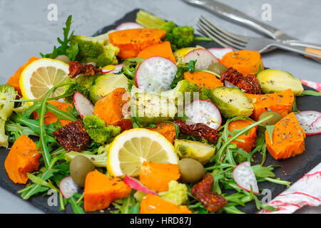 Cotto a vapore la patata dolce, broccoli e altre verdure su insalata di ardesia. Amore per un sano cibo vegan concept Foto Stock