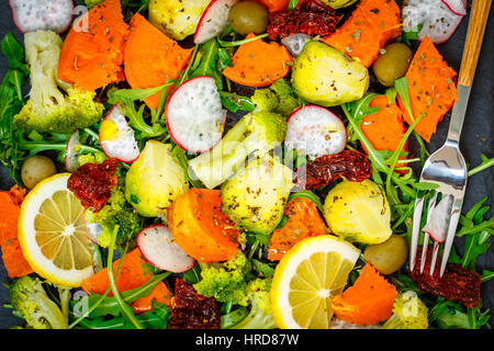 Cotto a vapore la patata dolce, broccoli e altre verdure su insalata di ardesia. Amore per un sano cibo vegan concept Foto Stock