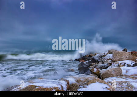 Mare onda invernale colpisce il frangiflutti. Nuvole temporalesche Foto Stock