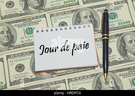 Pagina del notebook con testo francese JOUR DE PAGA (PAYDAY) sul background del dollaro Foto Stock